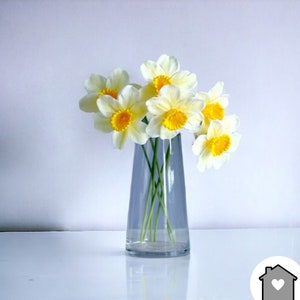 Artificial daffodil flower bouquet in clear vase with white petals and yellow centers
