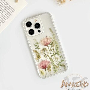 Transparent phone case with pink sakura flowers, green leaves, and camera cutouts