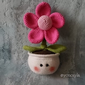 Crochet flower in fabric pot, pink five-petal bloom with green leaves and smiling face
