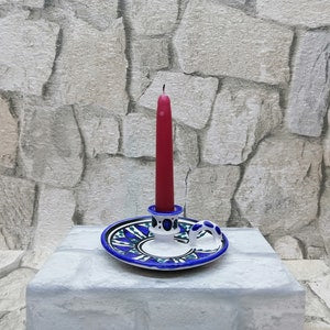 Ceramic candlestick holder with handle, blue-and-white base, red candle