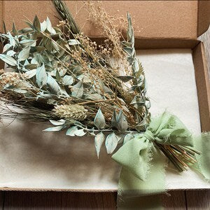Sage green dried flower bouquet with ribbon bow, laid in an open gift box