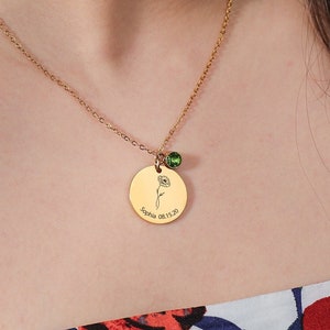 Gold-tone necklace with round engraved pendant and small green birth-flower charm