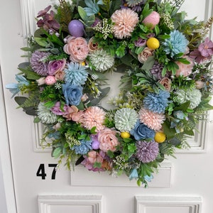 Pastel spring wreath with assorted flowers, greenery, and decorative eggs