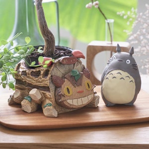 Totoro planter figure cover with character face and small plant display on stand