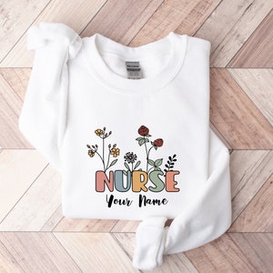 White nurse sweatshirt with floral design and 'NURSE Your Name' text