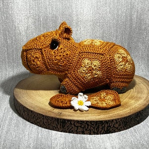 Crochet capybara plush toy in brown with small flower applique