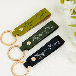 Personalized keychain with cursive name text and small flower pattern; green and black straps