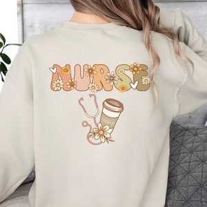 Cream sweatshirt with back graphic of floral stethoscope and wildflowers design