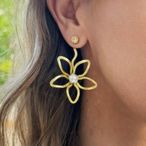 Gold flower earring jacket with pearl center and small stud on earlobe