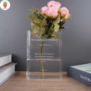 Clear acrylic book-shaped vase with pink and green floral bouquet