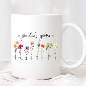 White ceramic mug with "Sandra's garden" text and colorful birth flower stems