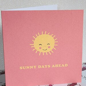 Pink greeting card with smiling yellow sun and text "Sunny Days Ahead"