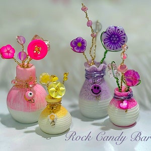 Mini beaded flower bouquet in pastel striped vases, pink and purple blooms