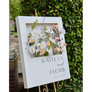 Polaroid-style welcome sign with floral panel and names Kaitlyn and Jacob