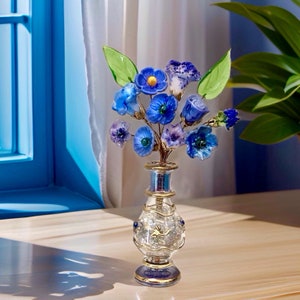 Glass wildflower bouquet in clear vase with blue flowers and green leaves