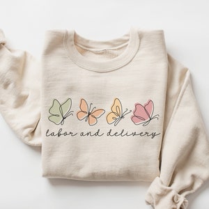 Cream sweatshirt with butterfly “labor and delivery” graphic and crew neckline
