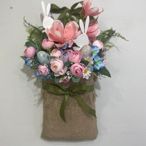 Wall hanging basket with pink and pastel faux flowers and green leaves, fabric bow