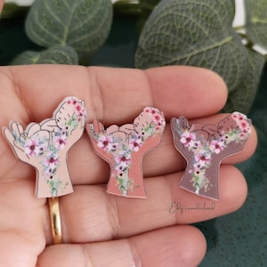 Floral baby-themed enamel brooch pins with pink flower designs, metal backing