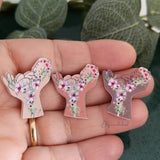 Pin newborn baby aesthetic style. Baby in hands with flowers brooch. Gift for midwife, doula.