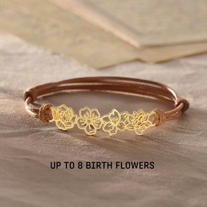 Gold-tone birth flower bracelet with small floral charm on brown cord