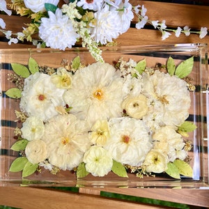 Acrylic flower preservation tray with pressed white blooms and green leaves