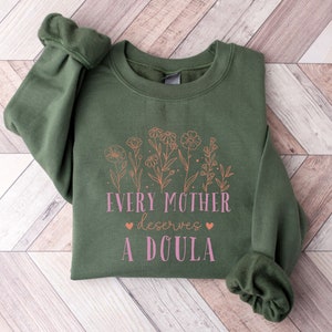 Dark green long-sleeve shirt with floral text: “Every mother deserves a doula”