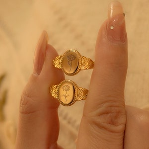 Gold birth-flower signet ring with engraved circular floral medallion