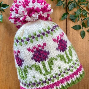 Knitted beanie hat with thistle flower pattern in purple, pink, and green