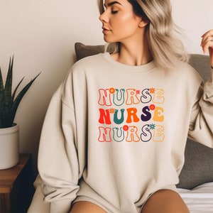 Beige nurse sweatshirt with colorful retro nurse word graphic