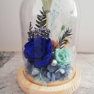 Glass dome preserved flower arrangement with blue and teal roses on a wooden base