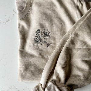 Light gray sweatshirt with embroidered floral line-art graphic on chest