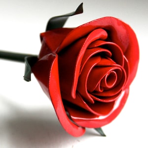 Red metal rose ornament with layered petals and green leaves