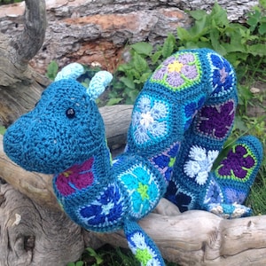 Blue crocheted ogopogo with multicolor African flower motifs