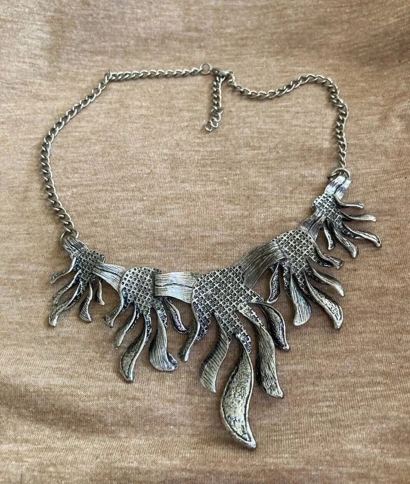 Silver tone statement collar necklace with dangling leaf-like charms and decorative links