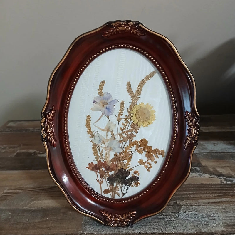 Oval wooden picture frame with ornate carving and pressed dried flowers art