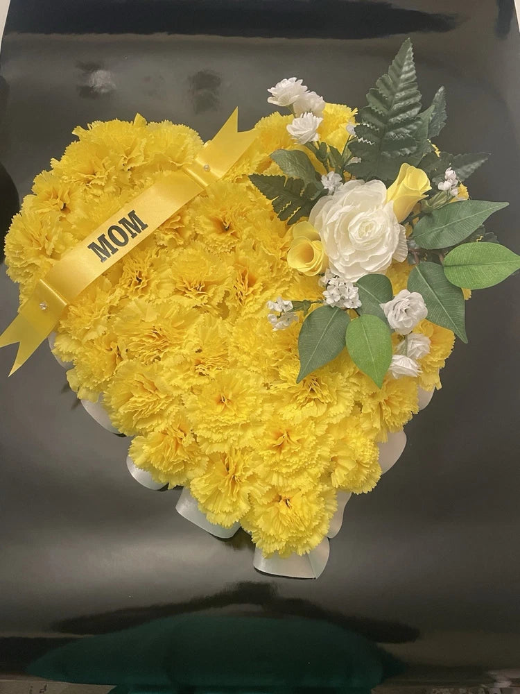 Heart-shaped memorial wreath with yellow flowers, white roses, and MOM ribbon tag