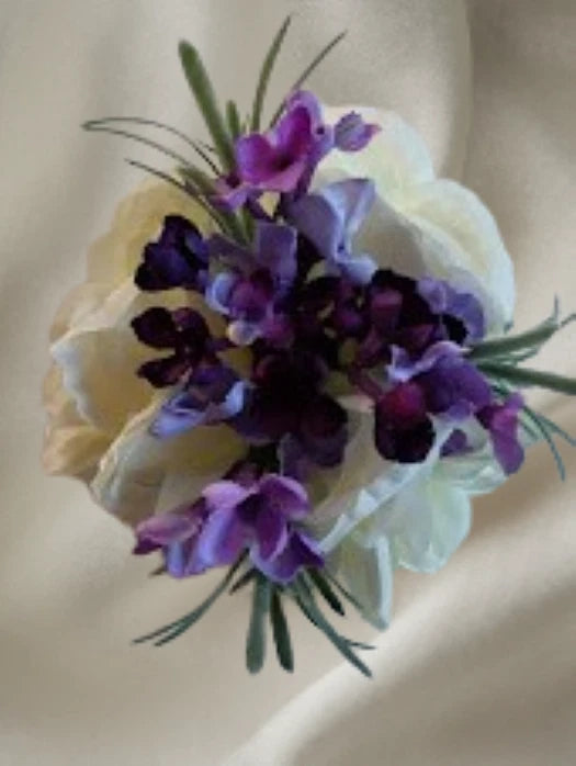 Lilac and purple wrist corsage bouquet with rose-like blooms and green leaves