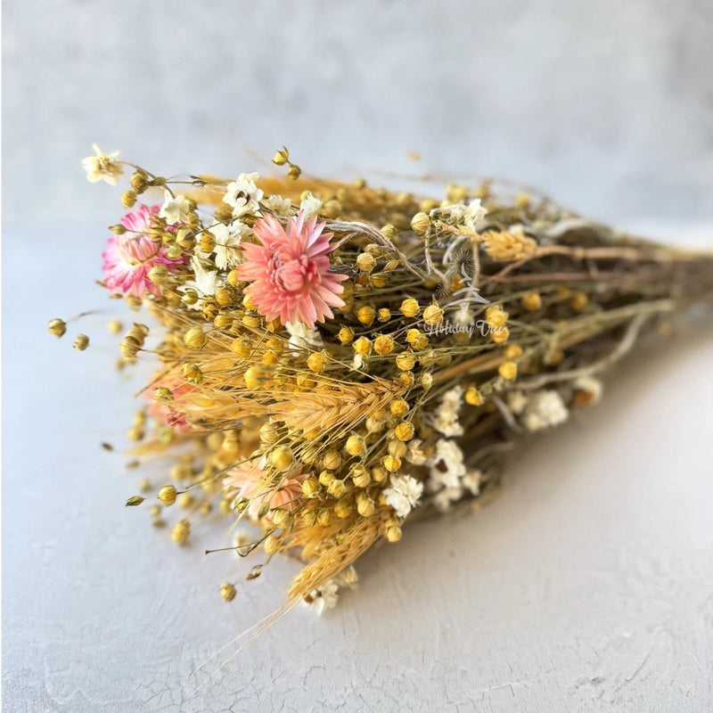 Dried flower bouquet with pink, cream, and golden blooms on a natural bundle