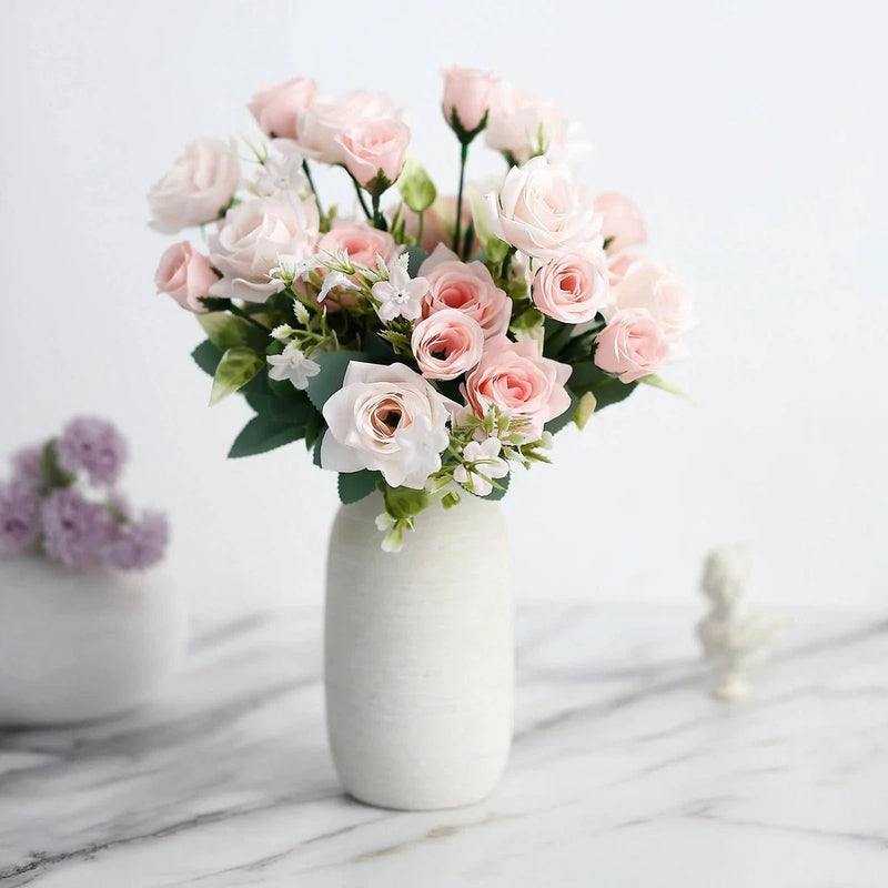 Artificial blush pink rose bouquet with white blooms and green leaves in white vase