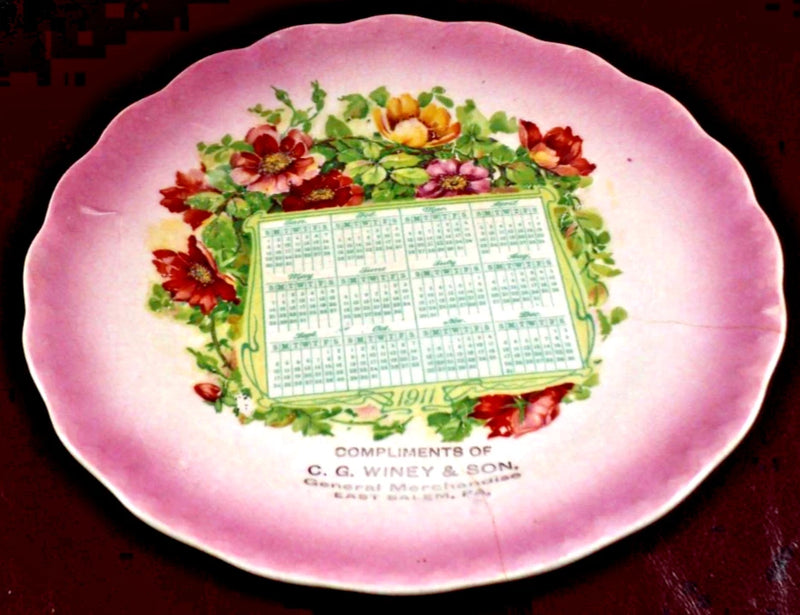 Pink ceramic calendar plate with floral wreath and 1911 date grid in center