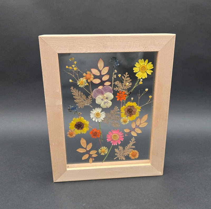 Light wood framed pressed flowers botanical art with multicolor blooms on blue