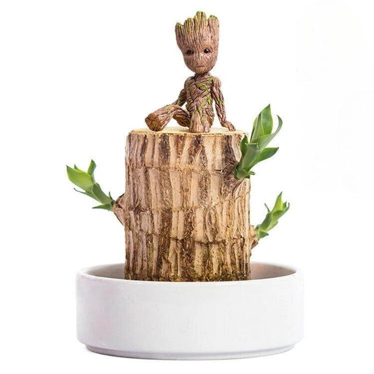 Decorative potted wood tree figurine with carved character and green leaves in white planter