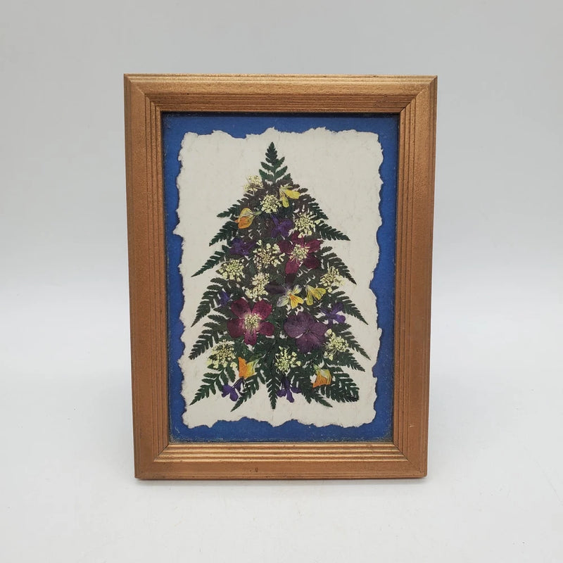 Wooden-framed pressed flower Christmas tree wall art with blue background and white mat