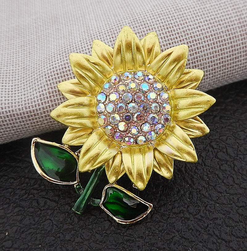 Gold enamel sunflower brooch with crystal center and green leaf accents