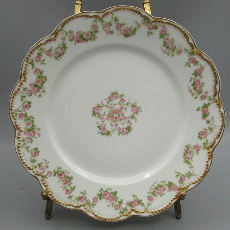 Round porcelain luncheon plate with scalloped rim, gold trim, pink rose garland pattern