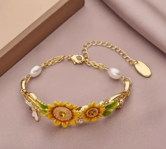Gold-tone bracelet with sunflower charms, dangling pearl beads, and clasp closure