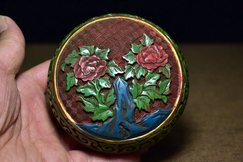 Round lacquer jewelry box lid with carved peony flowers in red, green, and gold