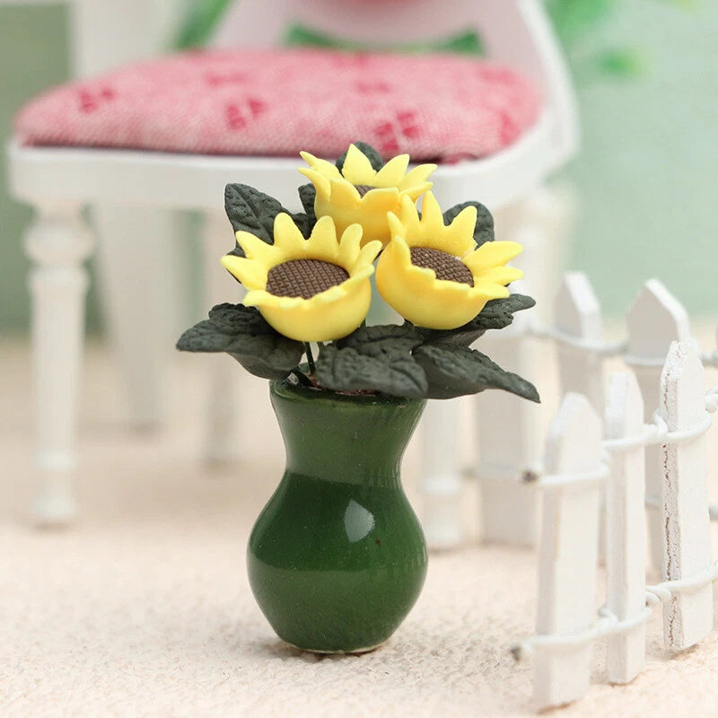 Miniature green vase with two yellow sunflower blooms and dark green leaves