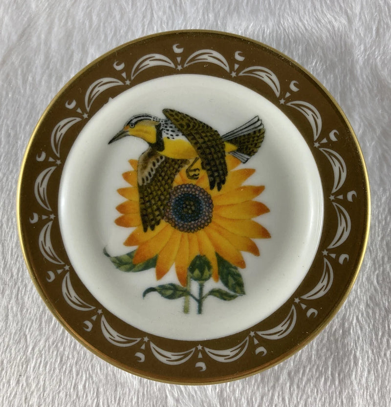 Gold-rimmed miniature plate with meadowlark bird and sunflower illustration in center