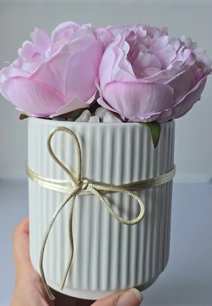 Pink faux peony silk flowers in a white ribbed ceramic pot with gold satin bow